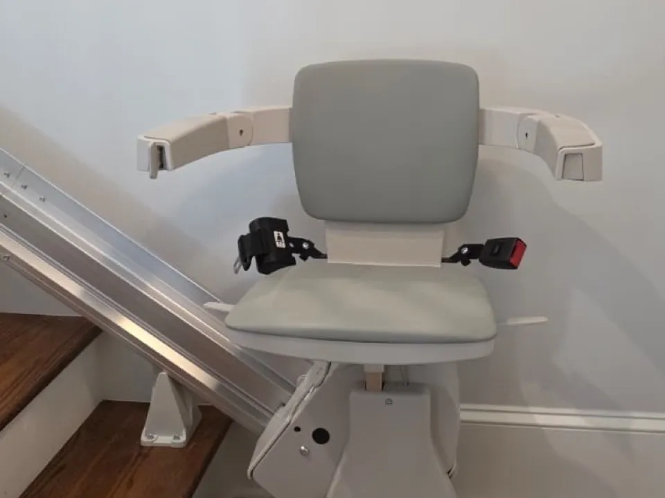 A straight stairlift fitted at the foot of a wooden staircase in a customer's home